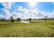 The expansive backyard features a pond, a home on the left, and sunny, partly cloudy skies at 16440 Cape Horn Blvd, Punta Gorda, FL 33955