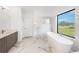 Modern bathroom showcases a soaking tub, marble tile, and a large window for natural light at 16440 Cape Horn Blvd, Punta Gorda, FL 33955