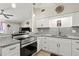 Modern kitchen boasts white cabinets, stainless steel appliances, granite countertops, and updated fixtures at 209 Seminole Nw Blvd, Port Charlotte, FL 33952