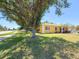 Well-maintained lawn with mature trees framing the house, creating a peaceful and inviting landscape at 22299 Catherine Ave, Port Charlotte, FL 33952