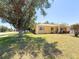 Beautiful home with lush lawn, mature trees, and a red colored driveway on a sunny day at 22299 Catherine Ave, Port Charlotte, FL 33952