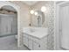 Bright bathroom featuring patterned wallpaper and round mirror above the sink at 22385 Olean Blvd, Port Charlotte, FL 33952