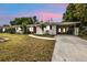 Charming one-story home with a well-manicured lawn, covered porch, and attached carport at sunset at 22385 Olean Blvd, Port Charlotte, FL 33952