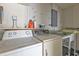 Functional laundry room with a washer, dryer, storage shelves, and utility sink at 22385 Olean Blvd, Port Charlotte, FL 33952