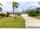 This home offers a manicured lawn, a paved driveway, lush tropical trees, and an inviting facade at 22448 Tennyson Ave, Port Charlotte, FL 33954