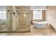 Bright bathroom featuring a soaking tub, glass shower and neutral tile flooring at 23240 Fullerton Ave, Punta Gorda, FL 33980