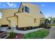 Side angle of a two-story yellow home with a well-kept lawn and a cozy porch with stairs at 25188 Marion Ave # 1015, Punta Gorda, FL 33950