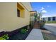 Low angle view of the side entrance and porch stairs to a yellow home with tidy landscaping at 25188 Marion Ave # 1015, Punta Gorda, FL 33950