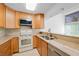 A kitchen featuring tile backsplash, tile floors, light wood cabinets, and stainless steel appliances at 25188 Marion Ave # 1015, Punta Gorda, FL 33950