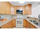 A well-lit kitchen features tile backsplash, wood cabinets, and modern stainless steel appliances at 25188 Marion Ave # 1015, Punta Gorda, FL 33950