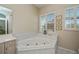 Corner bathtub with jets, a window with wooden blinds, and white tiled walls at 26089 Templar Ln, Punta Gorda, FL 33983