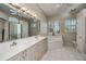 Spacious bathroom with double sinks, bathtub, large mirror, vanity lighting, and a window at 26089 Templar Ln, Punta Gorda, FL 33983