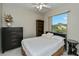 Cozy bedroom with a comfortable bed, large window, ceiling fan, dark dresser, and bookshelf at 26089 Templar Ln, Punta Gorda, FL 33983