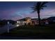 Well-maintained house featuring a paved driveway, manicured lawn and landscaped garden at dusk at 26089 Templar Ln, Punta Gorda, FL 33983