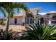 Charming home featuring a manicured lawn, vibrant tropical plants and elegant entry with security gate at 26089 Templar Ln, Punta Gorda, FL 33983