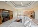 Open-concept living area with neutral tones, a tray ceiling, large TV, and views into the dining room and kitchen at 26089 Templar Ln, Punta Gorda, FL 33983