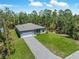 Aerial view of a new home with an expansive driveway and a lush green lawn surrounded by trees at 368 Manly St, Port Charlotte, FL 33953