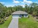 New construction home featuring a paved driveway and attached garage surrounded by a lush green lawn and mature trees at 368 Manly St, Port Charlotte, FL 33953