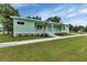Mint colored home with a white porch railing, manicured lawn and sidewalk at 535 Milus St, Punta Gorda, FL 33950