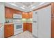 Well-lit kitchen featuring wooden cabinets, white appliances, and a tile floor at 601 Shreve St # 62A, Punta Gorda, FL 33950