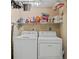 Organized laundry room with washer, dryer, storage shelf, and cleaning supplies at 601 Shreve St # 62A, Punta Gorda, FL 33950