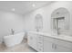 Bright bathroom features dual vanity, soaking tub, marble countertop and tiled floor at 7095 Beardsley St, Englewood, FL 34224
