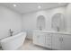 Modern bathroom featuring a soaking tub, dual sink vanity, and white cabinets at 7095 Beardsley St, Englewood, FL 34224