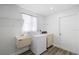 Functional laundry area includes a sink, washer, dryer, and storage shelf at 7095 Beardsley St, Englewood, FL 34224