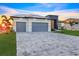 Front view of a modern home with a three-car garage, paver driveway, and manicured lawn at 9493 St Paul Dr, Port Charlotte, FL 33981
