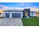 Modern home exterior featuring a three-car garage, contemporary design, and lush green lawn at 9493 St Paul Dr, Port Charlotte, FL 33981