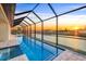 Enjoy this screened-in lanai with a pool and spa overlooking a canal at sunset at 9493 St Paul Dr, Port Charlotte, FL 33981