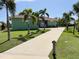 Charming single-story home featuring a well-manicured lawn, palm trees, and a long driveway leading to the entrance at 1315 Santiago Ct, Punta Gorda, FL 33950
