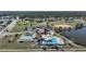 Aerial view of community amenities, including pool, tennis, shuffleboard, clubhouse, and picturesque pond at 13632 Clara Ln, Port Charlotte, FL 33981