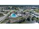 Aerial view of the community pool and clubhouse, featuring lounge chairs and palm trees by the pond at 13632 Clara Ln, Port Charlotte, FL 33981