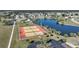 Overhead view displaying community tennis courts adjacent to a tranquil lake in a serene setting at 13632 Clara Ln, Port Charlotte, FL 33981