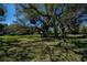 Grassy backyard provides plenty of shade thanks to the sprawling canopy of mature, moss-covered trees at 1420 Winding Oak Dr, Port Charlotte, FL 33948