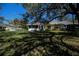 Well-maintained home with a charming screened-in lanai, surrounded by lush green grass and mature trees at 1420 Winding Oak Dr, Port Charlotte, FL 33948