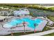 Aerial view of a large, modern community pool with lounge chairs and tennis courts in a lush, tropical setting at 14234 Heritage Landing Blvd # 1016, Punta Gorda, FL 33955