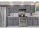 Updated kitchen with stainless appliances, gray cabinetry, and tile backsplash at 155 Francis Ne Dr, Port Charlotte, FL 33952