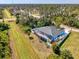 Aerial view of blue house with screened pool, complemented by green landscaping and surrounding trees at 1563 Arundel Ave, North Port, FL 34288