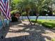 Lush front yard with rock beds, palm trees, and an American flag, creating a welcoming entrance at 1563 Arundel Ave, North Port, FL 34288