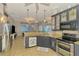 Spacious kitchen featuring stainless steel appliances, granite countertops, gray cabinets, and a view into the Gathering room at 1563 Arundel Ave, North Port, FL 34288