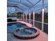 Inviting pool and spa area under a screened enclosure with ambient lighting for evening enjoyment at 1563 Arundel Ave, North Port, FL 34288