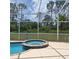 Inviting screened-in pool with an attached spa, surrounded by lush greenery, perfect for relaxation and outdoor enjoyment at 1563 Arundel Ave, North Port, FL 34288