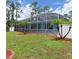 Backyard view showcasing the screened pool enclosure, lush lawn, and well-maintained landscaping, enhancing outdoor appeal at 1563 Arundel Ave, North Port, FL 34288
