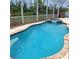 Inviting screened-in pool with an attached spa, surrounded by lush greenery, perfect for relaxation and outdoor enjoyment at 1563 Arundel Ave, North Port, FL 34288