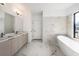 Elegant bathroom featuring a soaking tub, double vanity, and marble-style tile flooring at 17013 Alpenhorn Ct, Punta Gorda, FL 33955