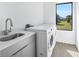 Well-equipped laundry room with modern washer, dryer, sink, and cabinets at 17013 Alpenhorn Ct, Punta Gorda, FL 33955