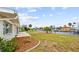 Beautiful backyard with green grass, tropical landscaping, and waterfront canal views at 1756 Boca Raton Ct, Punta Gorda, FL 33950