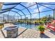 Screened pool area with a fire pit, patio furniture, and landscaping with a lake view in the background at 1849 E Isles Rd, Port Charlotte, FL 33953